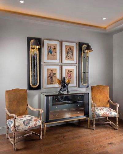 Foyer with mirrored console, framed ethnic art, sconces, and floral armchairs
