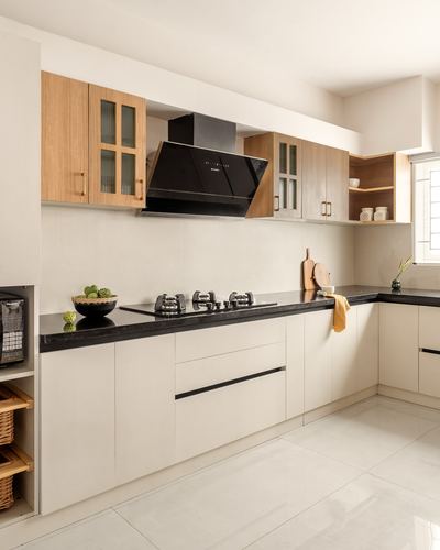 L-shaped kitchen with cream cabinets, wood-toned upper units, and black countertop