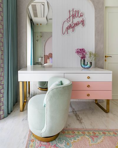 Mint velvet swivel chair before a white and pink vanity with neon sign and arched mirror