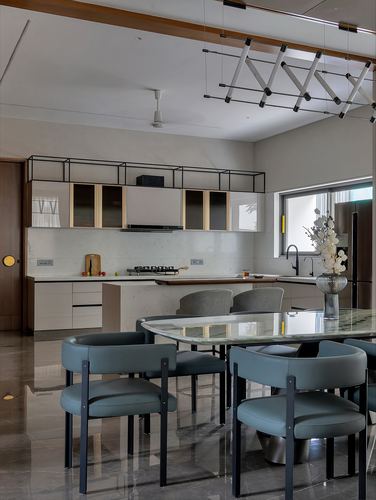 Open kitchen and dining area with marble floor, blue leather chairs, and scissor-arm pendant light