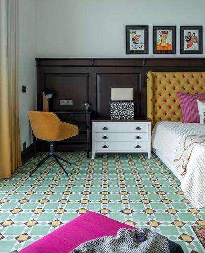 Bedroom with mustard tufted headboard, dark wood panelling, and patterned green cement tile floor