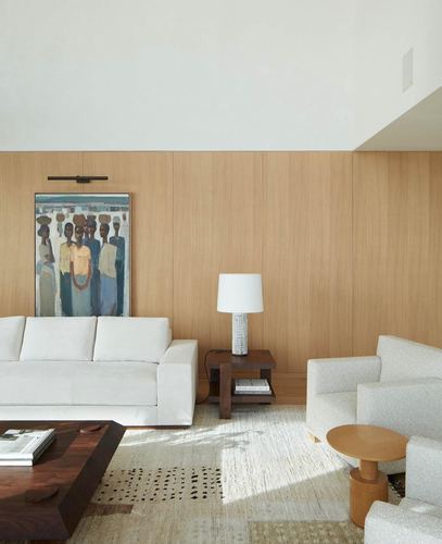 Neutral living room with wood-panelled wall, white sofa, boucle armchairs and a figurative painting