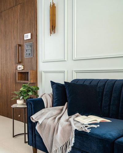 Navy velvet channel-tufted sofa against sage panelled wall with fluted wood partition and brass sconce