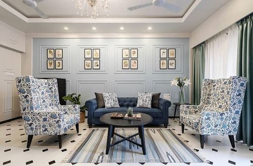 Living room with blue paneled wall, floral wingback chairs, navy tufted sofa and patterned rug