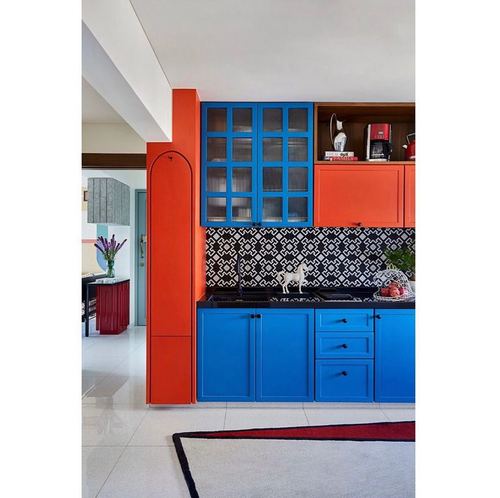 Bright blue and orange kitchen cabinetry with patterned black-and-white backsplash tile