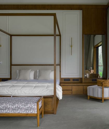 Bedroom with teak four-poster bed, built-in dresser, mirror, and stone floor