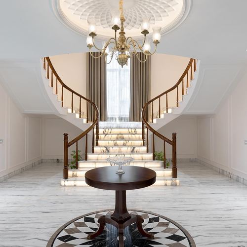 Symmetrical foyer with double curved marble staircase, chandelier, and round table