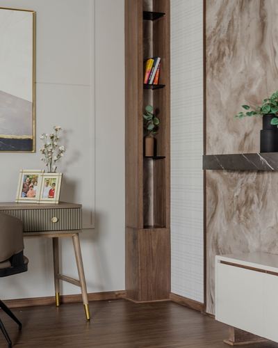 Corner of a study with wood display niche, marble-clad wall, and console table with framed photos