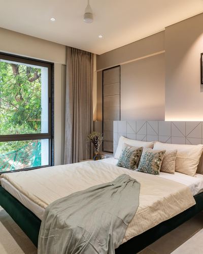 Bedroom with green velvet bed, patterned headboard, and large window overlooking trees