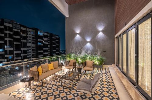 Night balcony lounge with patterned tile floor, rattan seating, and city skyline view