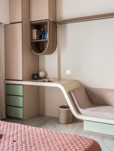 Curved wooden desk flowing into pink upholstered bench beside pastel storage cabinetry in a child's bedroom