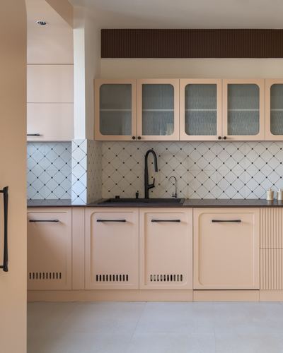 Peach kitchen with patterned tile backsplash, black countertop, and ribbed glass cabinet doors