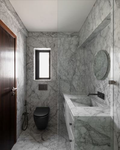 Marble-clad bathroom with black wall-hung toilet, round mirror and glass shower partition