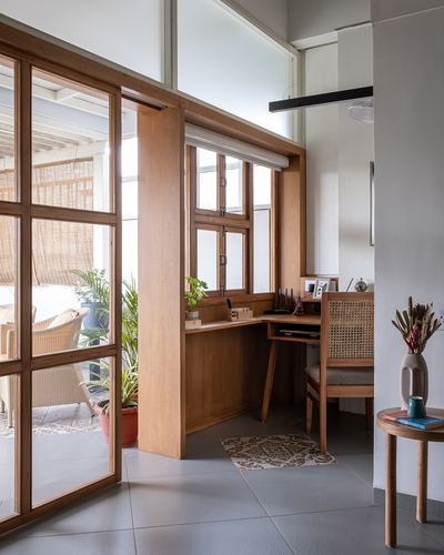 Wooden study nook with cane chair beside glass sliding doors and balcony view