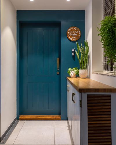 Entry foyer with teal door, wooden threshold, and console table with plants