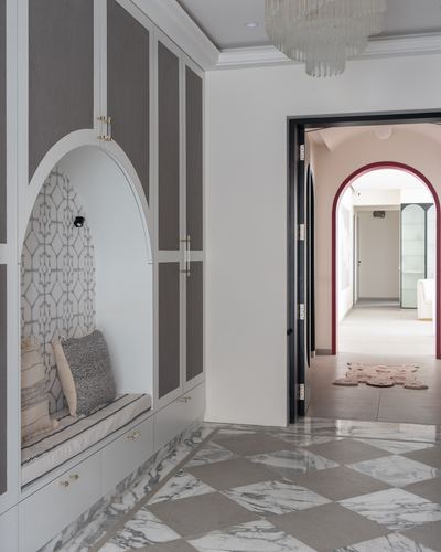 Foyer with arched wardrobe seating nook, diamond marble floor, and view through arched doorway to pink hallway