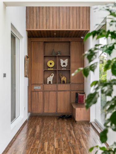 Wood-paneled foyer with open display shelves holding decorative objects and a bench