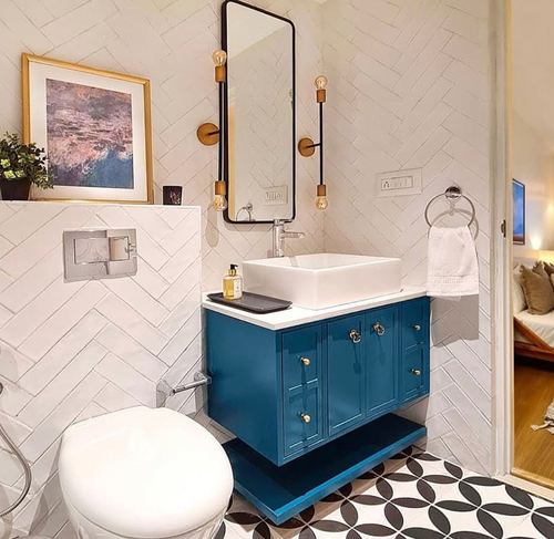 White herringbone-tiled bathroom with teal vanity, vessel sink, and patterned black-and-white floor