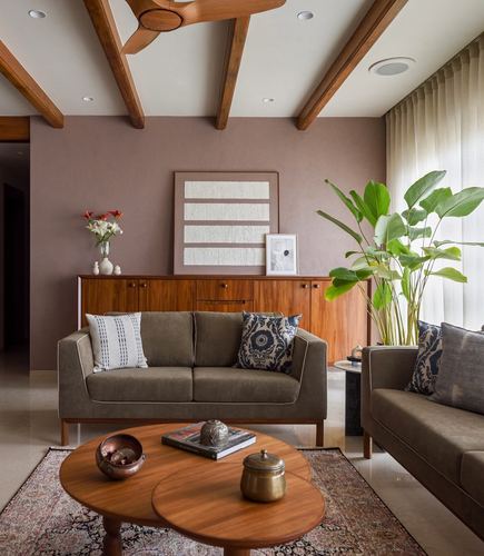 Living room with mauve wall, wooden beam ceiling, olive sofas and round wood coffee tables