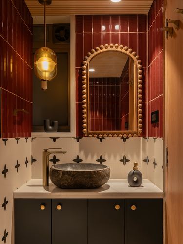 Bathroom vanity with stone vessel sink, arched beaded mirror, and red fluted tile walls