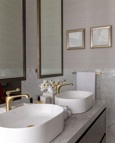 Double vanity bathroom with white vessel sinks, gold faucets, marble counter and framed mirrors