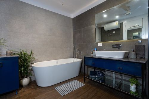 Modern bathroom with oval freestanding tub, navy vanity, and large mirror over vessel sink