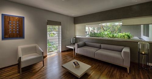 Minimalist living room with grey sofa, wood floor, and long window strip showing greenery