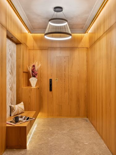 Wood-panelled foyer with layered pendant light, stone floor, and built-in bench with vase and cushion