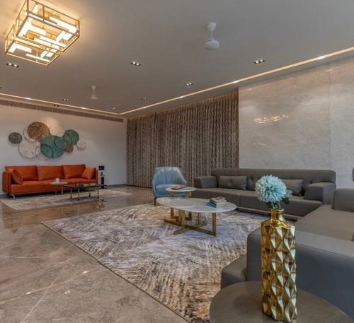 Spacious living room with grey sofas, terracotta couch, marble table and circular disc wall art