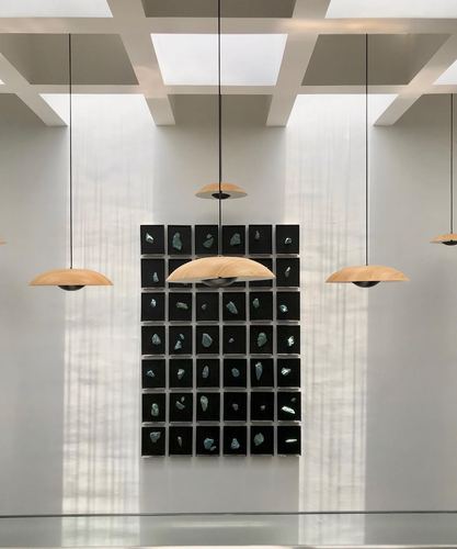 Minimalist white hallway with coffered skylight ceiling, wood-domed pendant lights, and a grid wall art panel