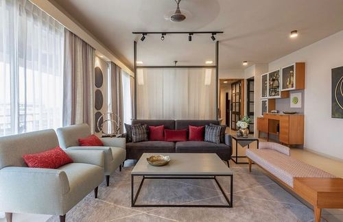 Minimalist living room with grey sofas, red cushions, and sheer fabric room divider