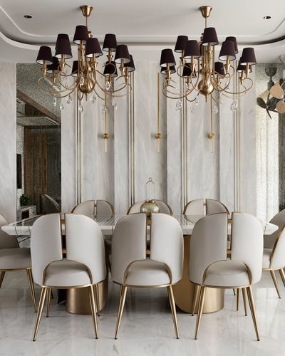 Dining room with twin gold chandeliers, marble table, and cream leather chairs with brass legs