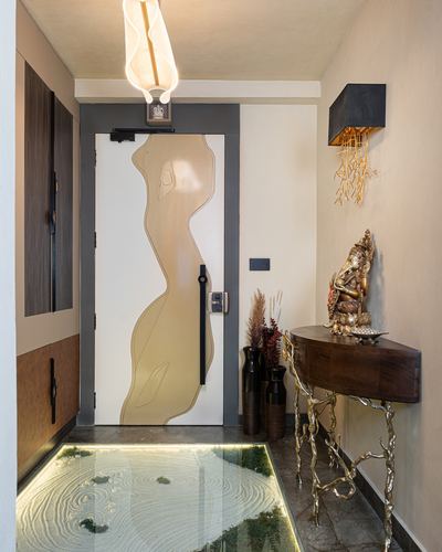 Foyer with carved organic-pattern door, glowing floor inlay, and brass console table with Ganesha idol