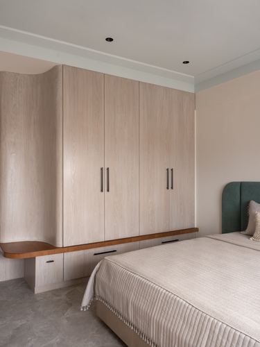 Bedroom with light wood wardrobe wall, curved corner unit, and green velvet headboard bed