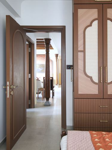 Open arched wooden door in bedroom looks down a hallway lined with turned wooden columns