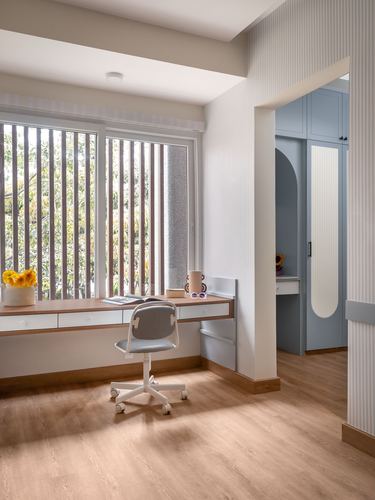Study nook with floating wood desk beside window, opening to blue arched wardrobe niche