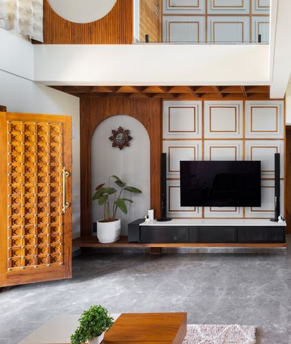 Living room with carved wooden door, arched niche clock, and panelled tv wall on marble floor