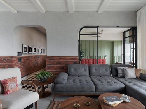 Grey sectional sofa in living room with brick archway and green-paneled corridor beyond
