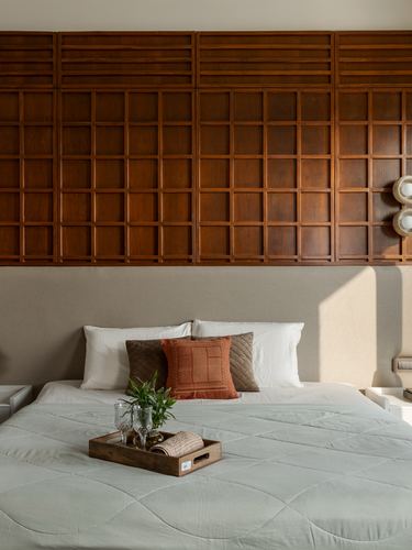 Bed against upholstered headboard beneath a large wooden grid-pattern panelled wall