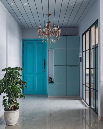 Foyer with teal paneled door, matching teal wardrobe, chandelier, and marble-look floor