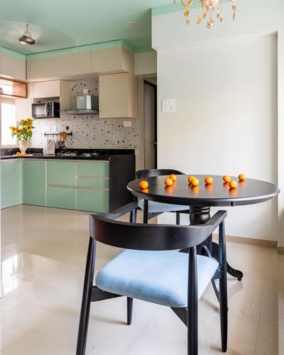 Open kitchen with mint cabinetry and terrazzo backsplash beside a round black dining table