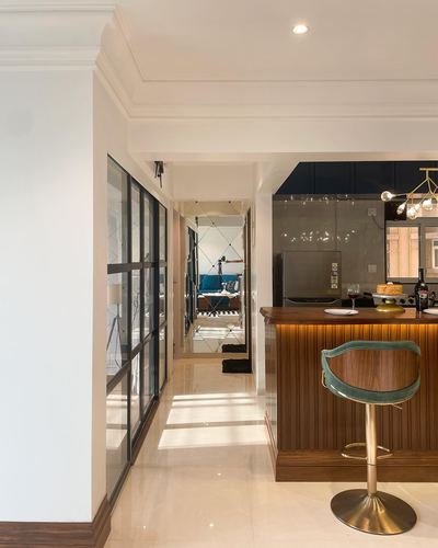 Ribbed wood bar counter with teal stool leads to a mirrored kitchen down a crittall-glazed hallway