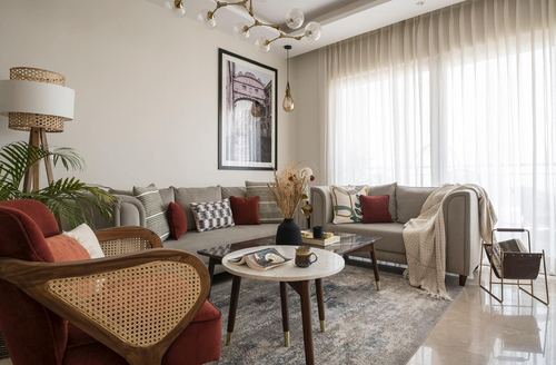 Living room with beige sectional, red cane armchairs, marble coffee table and sheer-curtained window