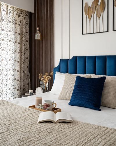 Bed with navy velvet channel headboard, beige linens, open book, and fluted wood wall panel