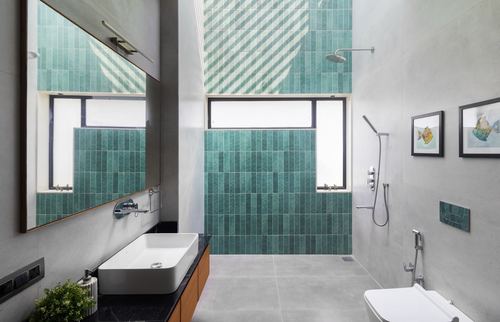 Bathroom with teal zellige tile wall, grey concrete surfaces, black stone vanity and wall-hung sink