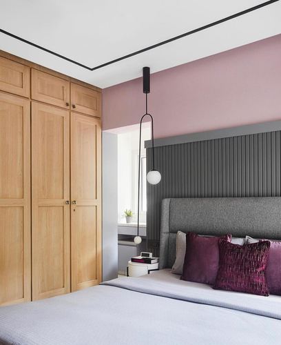 Bedroom with pink wall, wood wardrobe, ribbed grey headboard, and plum cushions