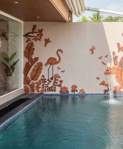 Poolside terrace with terracotta relief mural of flamingo and birds, water spout, and glass door