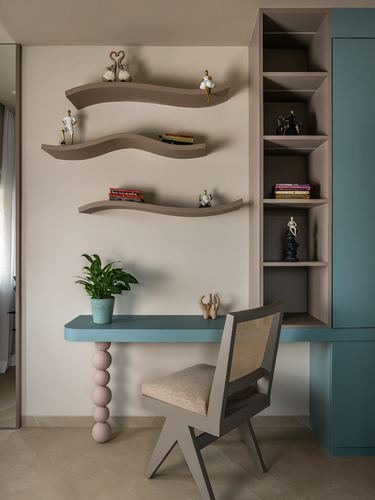 Study nook with curvy floating shelves, built-in bookcase, teal desk and cane-back chair