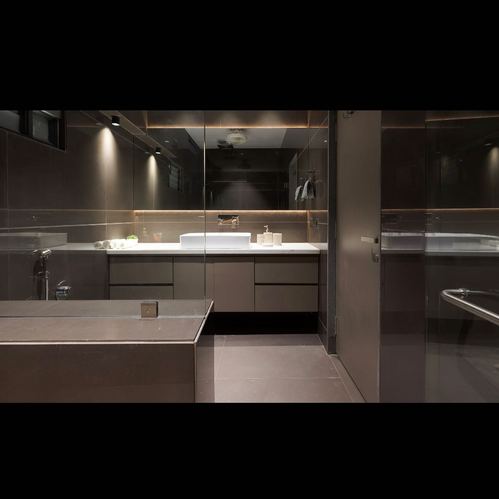 Dark brown bathroom with backlit mirror, vessel sink, and glass shower partition