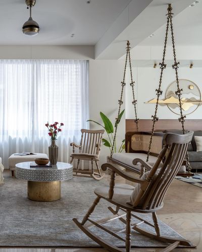 Living room with hanging wooden swing, rocking chairs, and round marble-topped coffee table